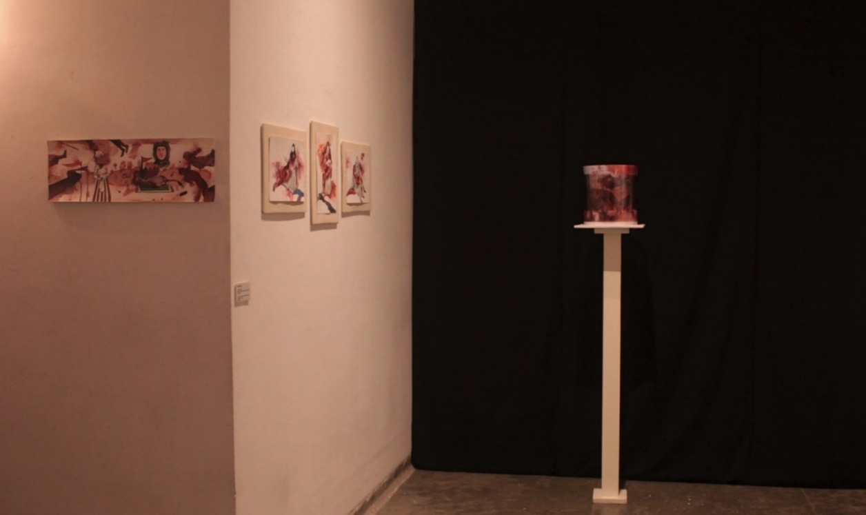 Exhibition installation view at 1 Shanti Road, Bangalore — a panoramic watercolor drawing hangs on the left wall, three photo ink paintings on Canson paper are mounted in the center, and the kinetic installation on a white pedestal stands to the right against a black curtain. Next Step Residency Program, 2019.
