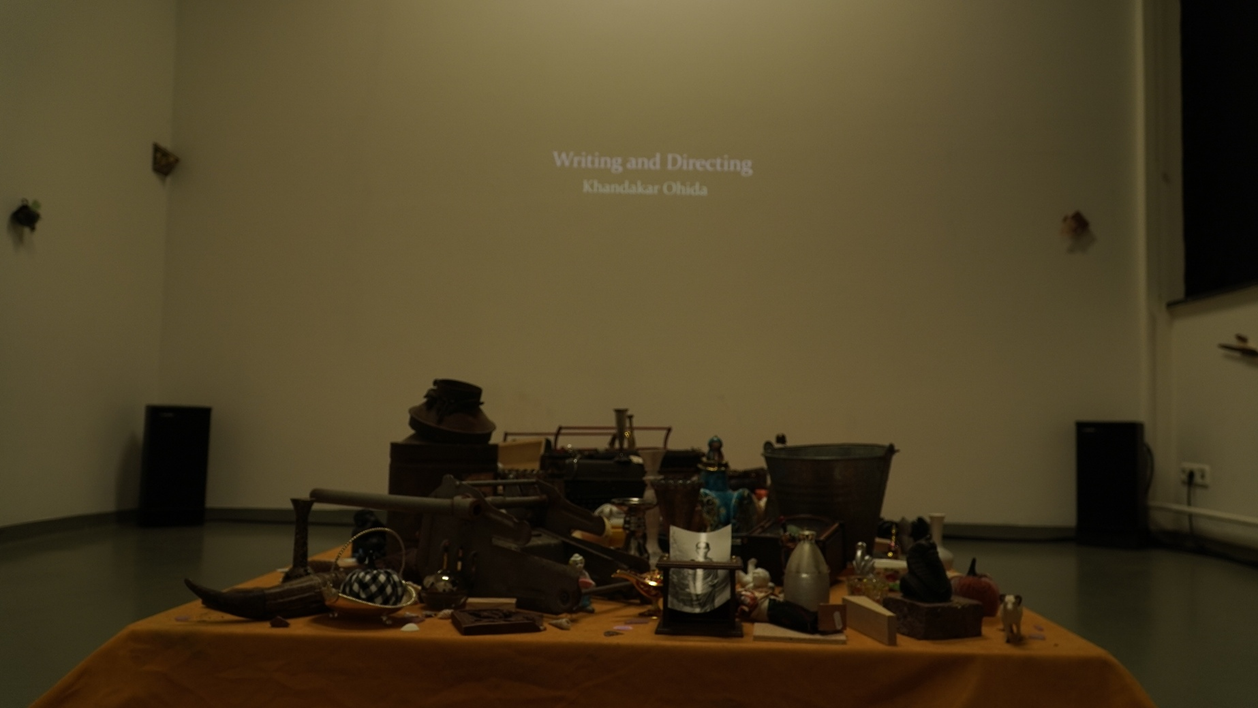 Film still — scattered handwritten documents and papers spread across a surface, fragments of personal and institutional record-keeping.
